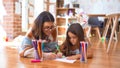 Beautiful teacher and toddler drawing using pencils and paper around lots of toys at kindergarten Royalty Free Stock Photo