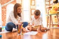 Beautiful teacher and toddler drawing using pencils and paper around lots of toys at kindergarten Royalty Free Stock Photo