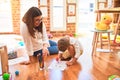 Beautiful teacher and toddler drawing using pencils and paper around lots of toys at kindergarten Royalty Free Stock Photo