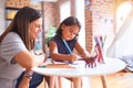 Beautiful teacher and toddler girl drawing draw using colored pencils at kindergarten Royalty Free Stock Photo