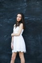 A beautiful teen brunette girl with a serious look leaning against a black wall Royalty Free Stock Photo
