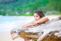 Beautiful teen girl on beach praying by driftwood log Royalty Free Stock Photo