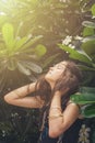 Beautiful teen girl in black tank top with plumeria tree in sun rays. Boho style portrait Royalty Free Stock Photo
