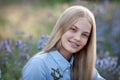 Beautiful teen girl with braces on her teeth smiling. portrait of blonde model with long hair in blue flowers Royalty Free Stock Photo