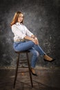 Beautiful teen girl dressed in blue jeans and white shirt sitting on chair studio portrait. Royalty Free Stock Photo