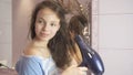 Beautiful teen girl dries hair a hairdryer in bathroom Royalty Free Stock Photo