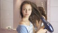 Beautiful teen girl dries hair a hairdryer in bathroom Royalty Free Stock Photo