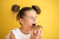 Beautiful teen girl eating a donut. emotionally laughing. on a yellow yak background. summer sunny picture Royalty Free Stock Photo