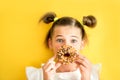 Beautiful teen girl eating a donut. emotionally laughing. on a yellow yak background. summer sunny picture Royalty Free Stock Photo