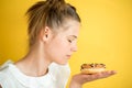 Beautiful teen girl eating a donut. emotionally laughing. on a yellow yak background. summer sunny picture Royalty Free Stock Photo