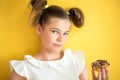 Beautiful teen girl eating a donut. emotionally laughing. on a yellow yak background. summer sunny picture Royalty Free Stock Photo