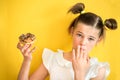 Beautiful teen girl eating a donut. emotionally laughing. on a yellow yak background. summer sunny picture Royalty Free Stock Photo