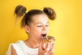 Beautiful teen girl eating a donut. emotionally laughing. on a yellow yak background. summer sunny picture Royalty Free Stock Photo