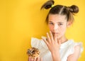 Beautiful teen girl eating a donut. emotionally laughing. on a yellow yak background. summer sunny picture Royalty Free Stock Photo