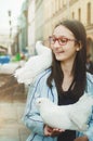 A beautiful teen girl with glasses laughs and looks at a white dove perched . Royalty Free Stock Photo
