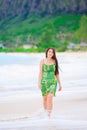 Beautiful teen girl in green dress walking along Hawaiian beach Royalty Free Stock Photo