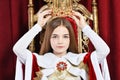 Beautiful teen girl holding crown sitting in vintage armchair Royalty Free Stock Photo