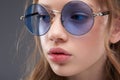 Beautiful teen girl with rosy full lips wearing blue round glasses