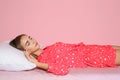 Beautiful teen girl sleeping with comfortable pillow o bed against color background Royalty Free Stock Photo