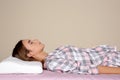 Beautiful teen girl sleeping with orthopedic pillow on bed against color background Royalty Free Stock Photo