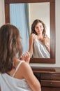 A beautiful teen girl studies her appearance as she looks into the mirror