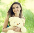 Beautiful teen girl with Teddy bear in the park at green grass. Royalty Free Stock Photo