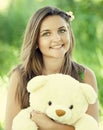 Beautiful teen girl with Teddy bear in the park at green grass. Royalty Free Stock Photo