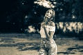 Beautiful teen girl wearing white bare shoulders top and jeans posing against trees on blurred nature background at Royalty Free Stock Photo