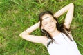 Beautiful teen girl in white dress lying on green grass, smiling, eyes closed. Top view. Boho style portrait Royalty Free Stock Photo