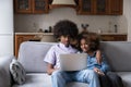 Beautiful teenage African couple sit on sofa with laptop Royalty Free Stock Photo