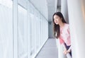 Beautiful teenage Asian girl wears a white with pink shirt and smiles cheerfully and confident while she stands near the glassed