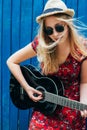 Beautiful teenage blonde long haired girl playing acoustic guitar outdoor. Vertical image Royalty Free Stock Photo