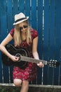 Beautiful teenage blonde long haired girl playing acoustic guitar outdoor. Vertical image. Royalty Free Stock Photo