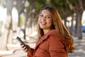 Beautiful teenage with coat looking at camera holding a smart phone Royalty Free Stock Photo