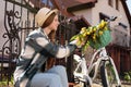 Beautiful teenage girl with bouquet of yellow tulips and bicycle outdoors near house Royalty Free Stock Photo