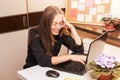 Beautiful teenage girl with glasses is studying or communicating at home on laptop at table. He smiles cheerfully and talks.