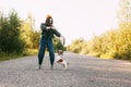 A beautiful teenage girl in a green jacket and orange hat plays with her dog while walking in the fresh air. The dog jumps up to Royalty Free Stock Photo