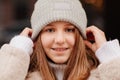 A beautiful teenage girl holds her hands on a warm knitted gray hat. New Year. Royalty Free Stock Photo