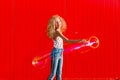 Beautiful teenage girl inflates soap bubbles against the red wall Royalty Free Stock Photo