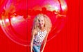 Beautiful teenage girl inflates soap bubbles against the red wall Royalty Free Stock Photo