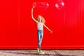 Beautiful teenage girl inflates soap bubbles against the red wall Royalty Free Stock Photo