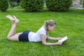 Beautiful teenage girl lies on green grass and reads book in park on summer sunny day Royalty Free Stock Photo