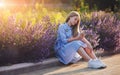 Beautiful teenage girl listening to music in headphones from smartphone. young happy model sitting outdoors in park flowers on Royalty Free Stock Photo