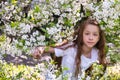 beautiful teenage girl with long blonde hair in white clothes enjoys the spring cherry blossom. Royalty Free Stock Photo