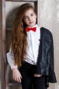 Studio portrait of a girl in a white shirt with a bow tie on a gray background Royalty Free Stock Photo