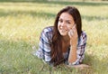 Beautiful teenage girl lying on field of green grass and talk by phone Royalty Free Stock Photo