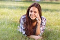 Beautiful teenage girl lying on field of green grass and talk by phone Royalty Free Stock Photo