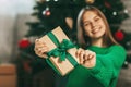 Beautiful teenage girl opens a gift made of kraft paper tied with a green ribbon, new year mood. Holiday concept of Christmas and Royalty Free Stock Photo