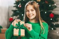 Beautiful teenage girl opens a gift made of kraft paper tied with a green ribbon, new year mood. Holiday concept of Christmas and Royalty Free Stock Photo