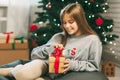 Beautiful teenage girl opens a gift made of kraft paper tied with a red ribbon, new year mood. Holiday concept of Christmas and Royalty Free Stock Photo